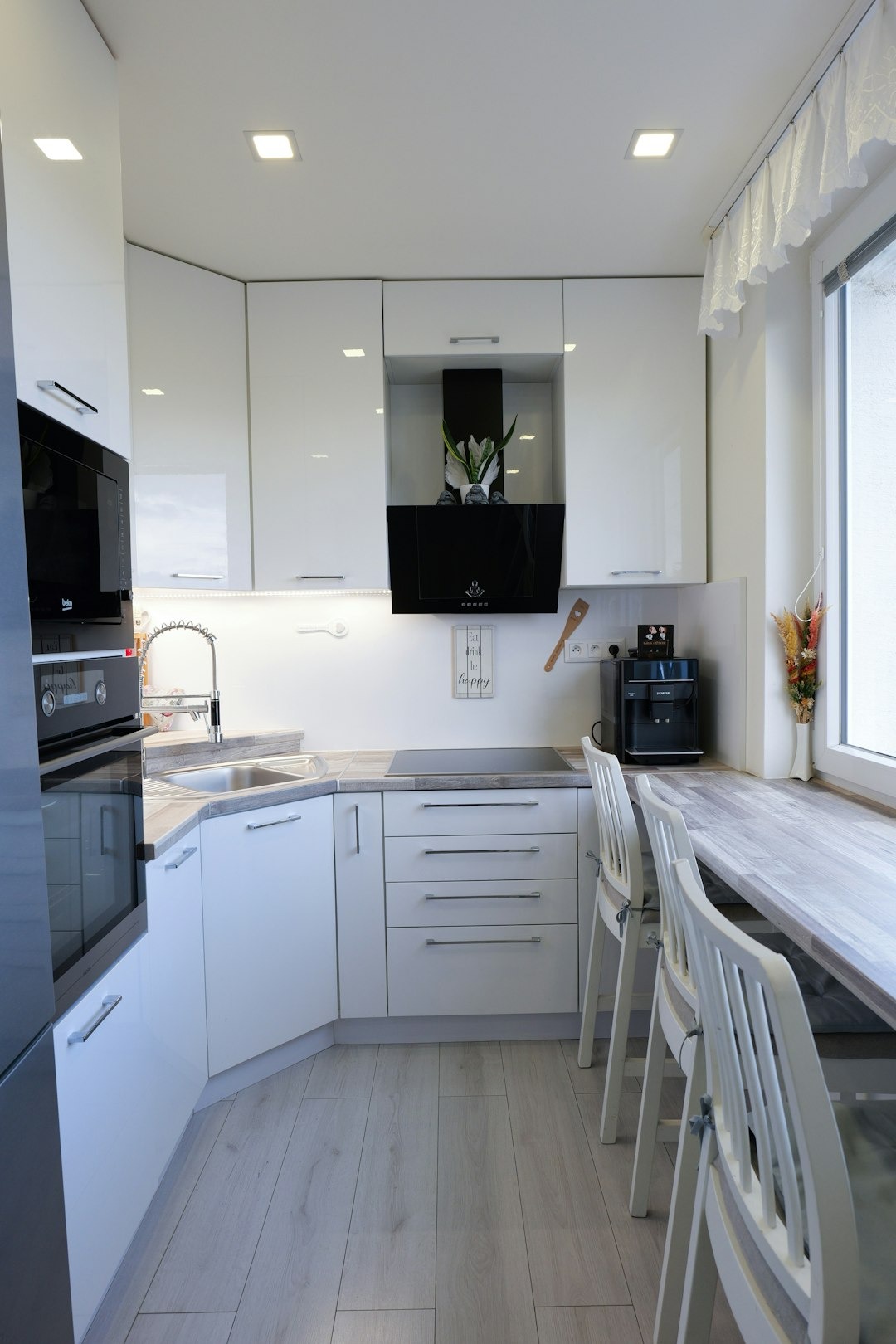 Modern compact kitchen with white cabinets and wood countertops.