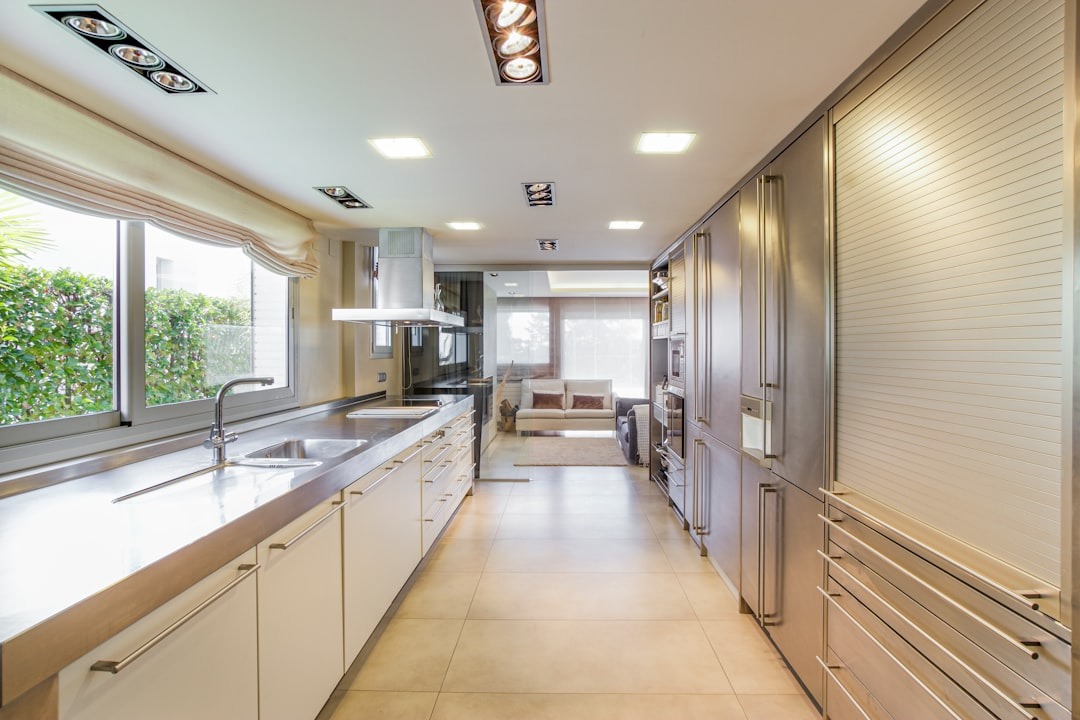 Modern galley kitchen with white cabinetry and stainless steel countertops.